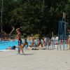 Persone a bordo piscina in un'area esterna con verde circostante.