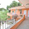 Balcone di un edificio arancione con porte, piante e sfondo verde.