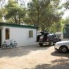 Un bungalow bianco con auto parcheggiate e biciclette fuori.