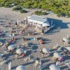 Spiaggia affollata con ombrelloni e chiosco.