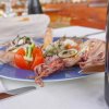 Piatto di frutti di mare e bicchiere di vino su un tavolo apparecchiato.