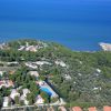 Vista aerea di una località costiera con piscine e vegetazione rigogliosa.