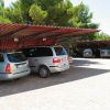 Parcheggio coperto con auto parcheggiate sotto tettoie rosse.
