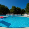 Piscina rotonda con lettini e ombrelloni.