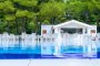Piscina con sedie bianche e bar immerso nel verde.