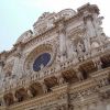 Facciata decorata di una chiesa con intricati rilievi e una grande rosetta.