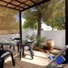 Terrazza coperta con tavolo, sedie e sdraio blu, circondata da un muro bianco e vegetazione.