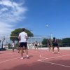 Partita di pallavolo all'aperto su campo rosso.