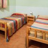Due letti singoli con copriletti colorati, un comodino e una lampada.