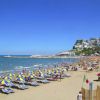 Spiaggia affollata con ombrelloni gialli e blu.