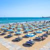 Ombrelloni blu e gialli in fila su una spiaggia soleggiata.